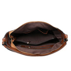 Sac bandoulière brun porté à la main
